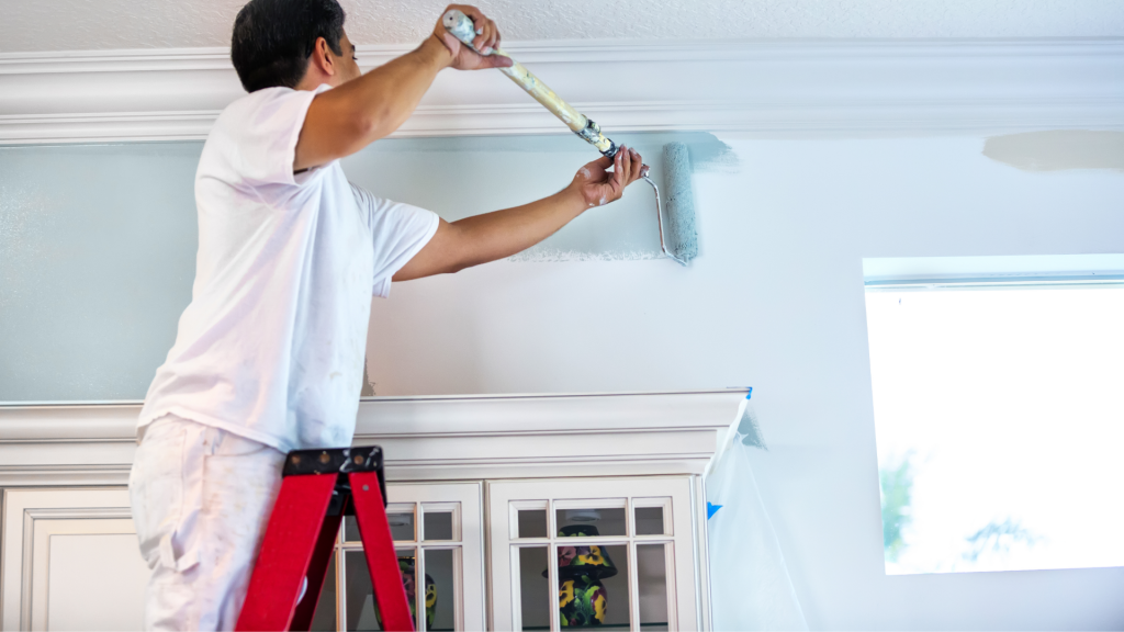 Un ouvrier en train de peindre le plafond d'une maison